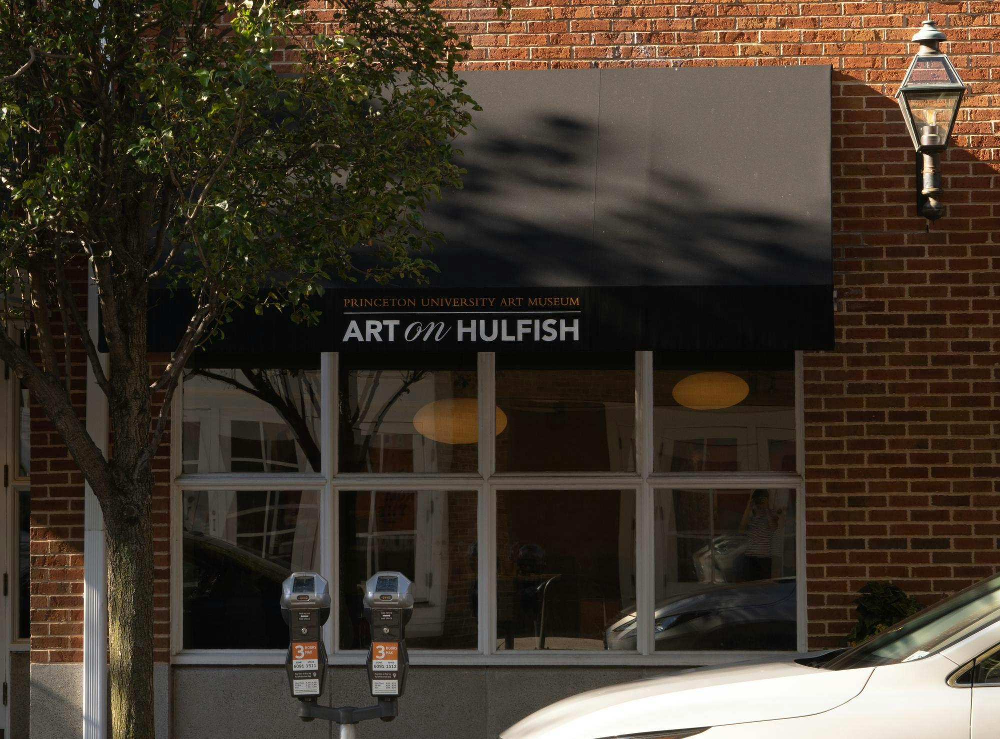 A window in a brick building is shaded by a black overhang that reads "Art on Hulfish"