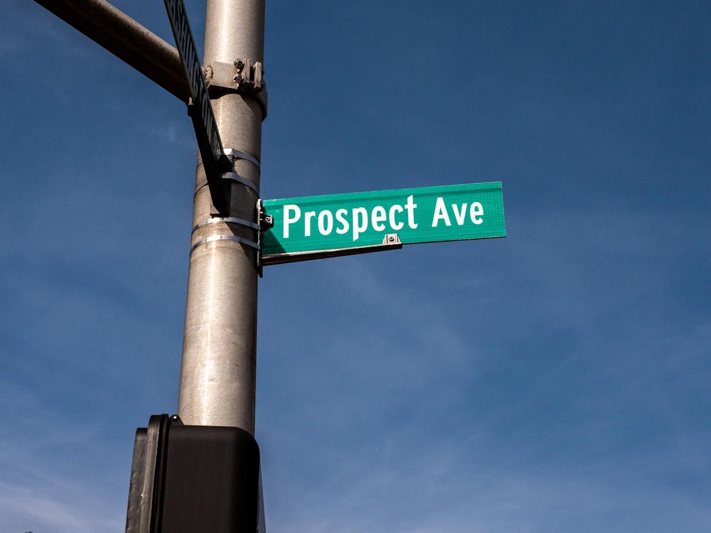 Prospect Avenue street sign with white letters on green sign attached to grey traffic pole.