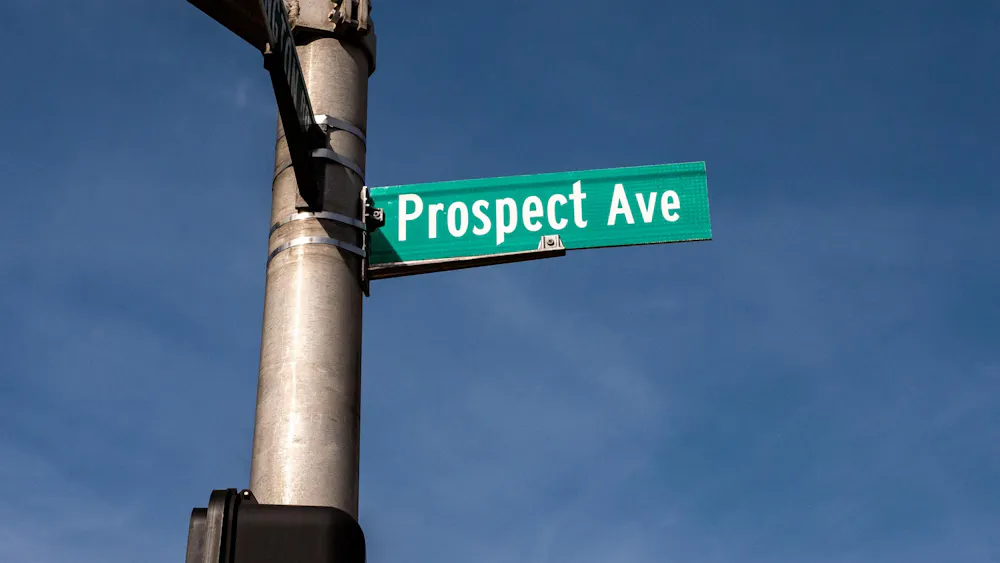Prospect Avenue street sign with white letters on green sign attached to grey traffic pole.