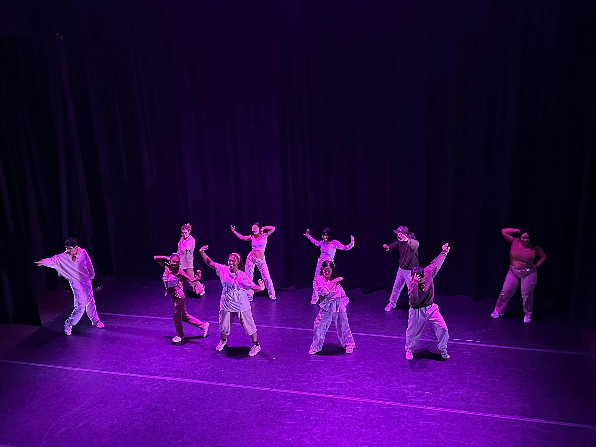 Ten BAC dancers dance to their choreography titled "status update" in Frist Theater with purple-pink lighting.