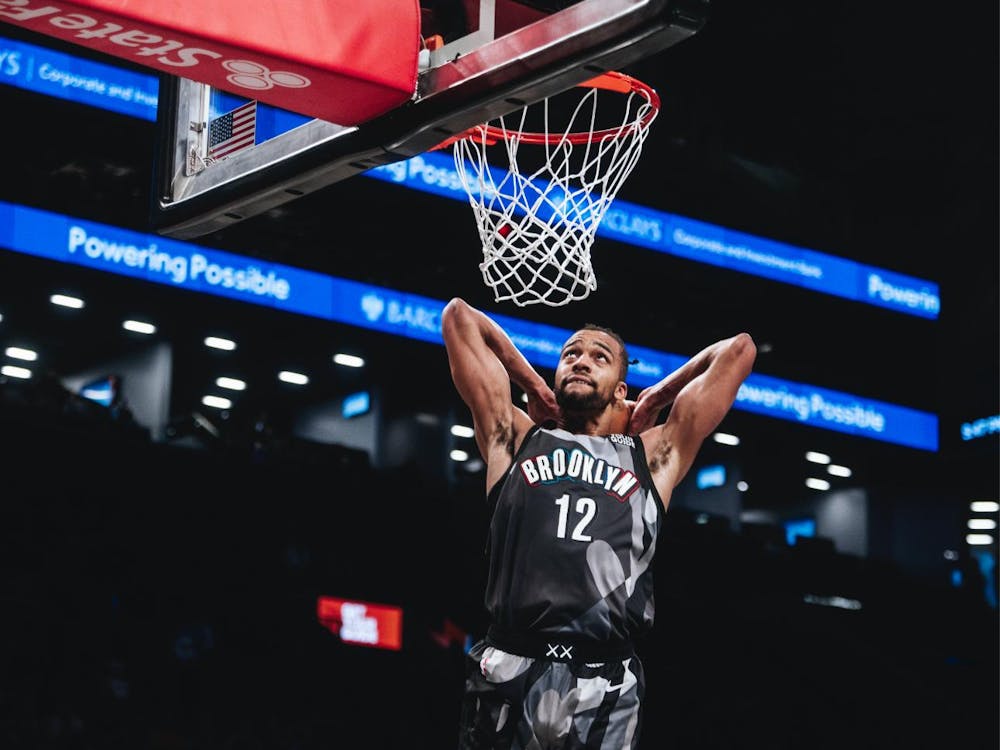 A man wearing a black and gray jersey that says “Brooklyn” dunking a basketball during a game.