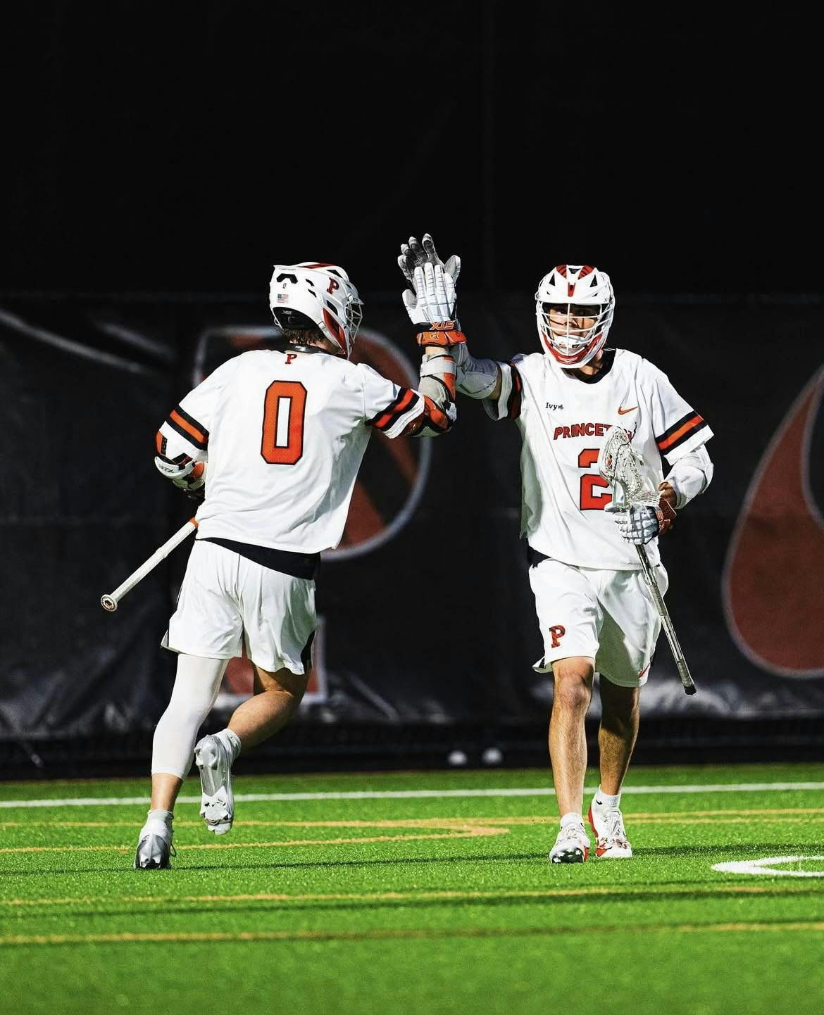 Lacrosse players in white jerseys celebrate 
