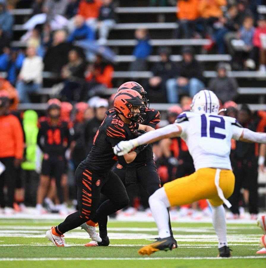 Football player in black receives football. 