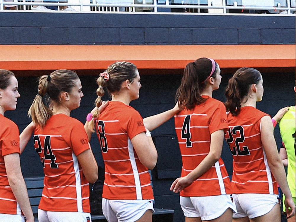 Women's soccer players standing in line with each girl's left arm on the left shoulder of the girl in front of them