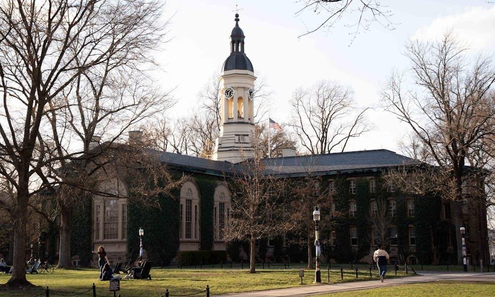 Un gran edificio cubierto de hiedra. Hay una torre de reloj en el centro. 