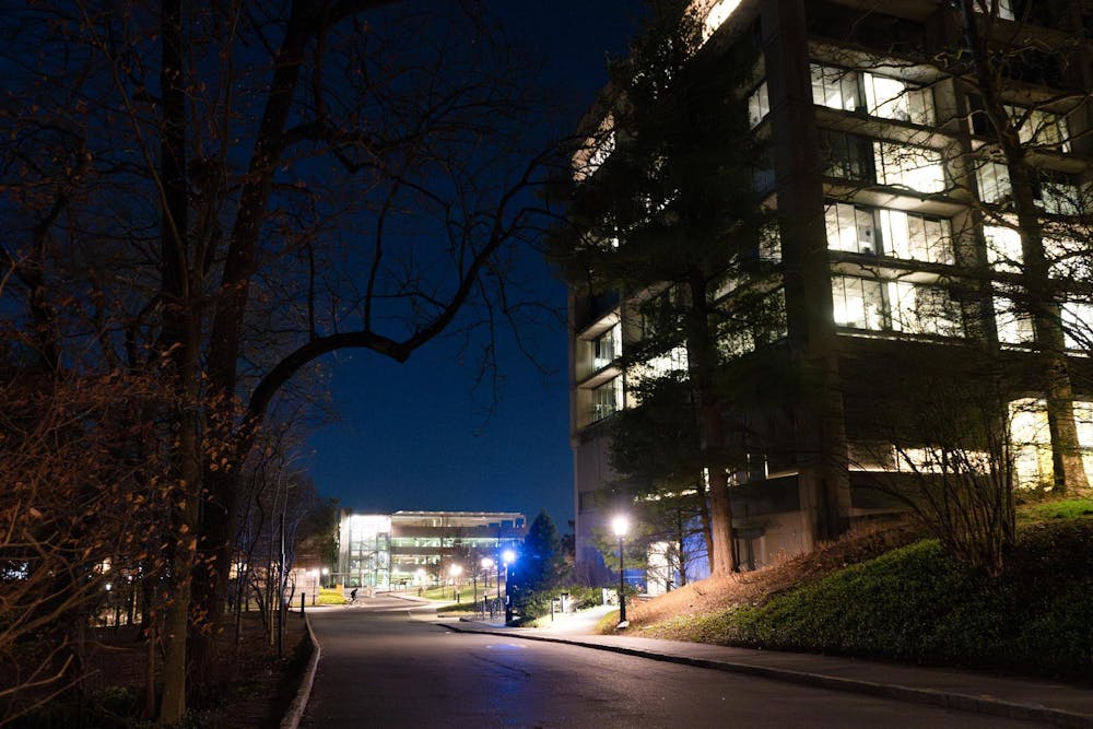 Dark street illuminated by lights on the right side with large stone building on the right.