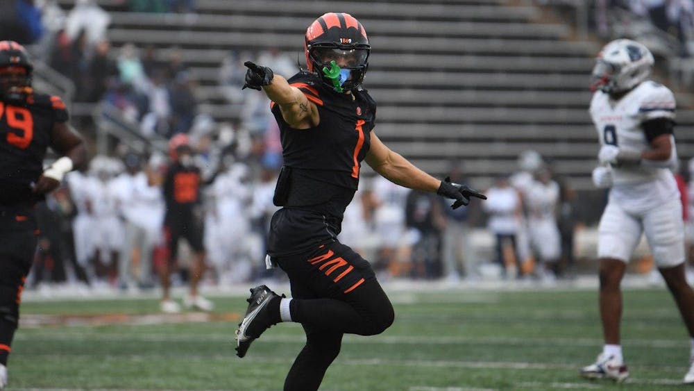 A football player in orange and black points with one foot up towards the endzone.