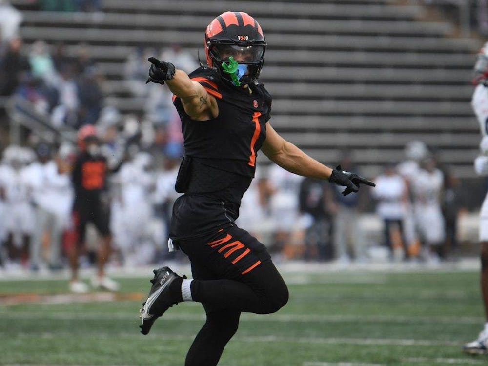 A football player in orange and black points with one foot up towards the endzone.