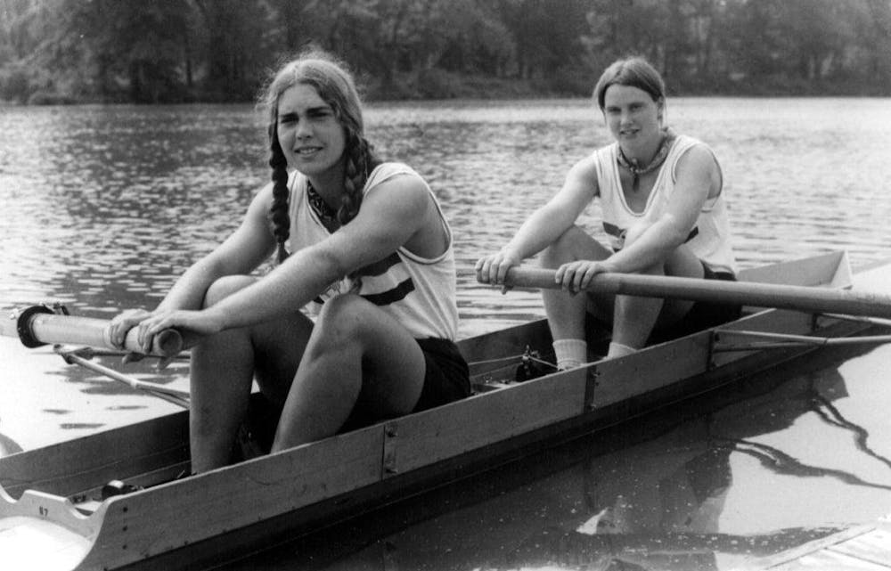 Two women rowing a boat on a lake.