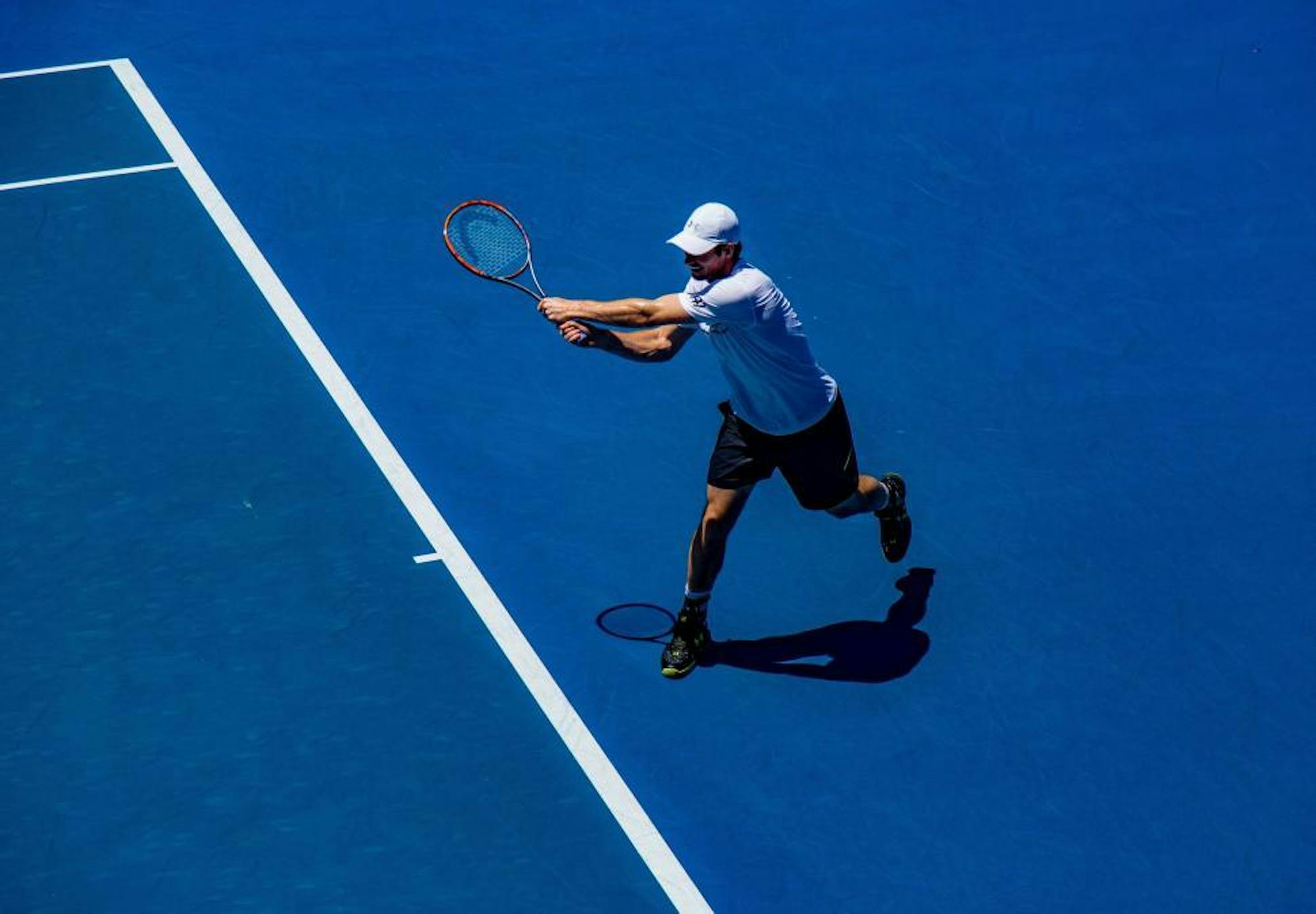 A tennis player on the court swinging his racket.