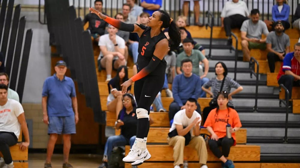 A woman jumping in the air and hitting a volleyball during a match. 