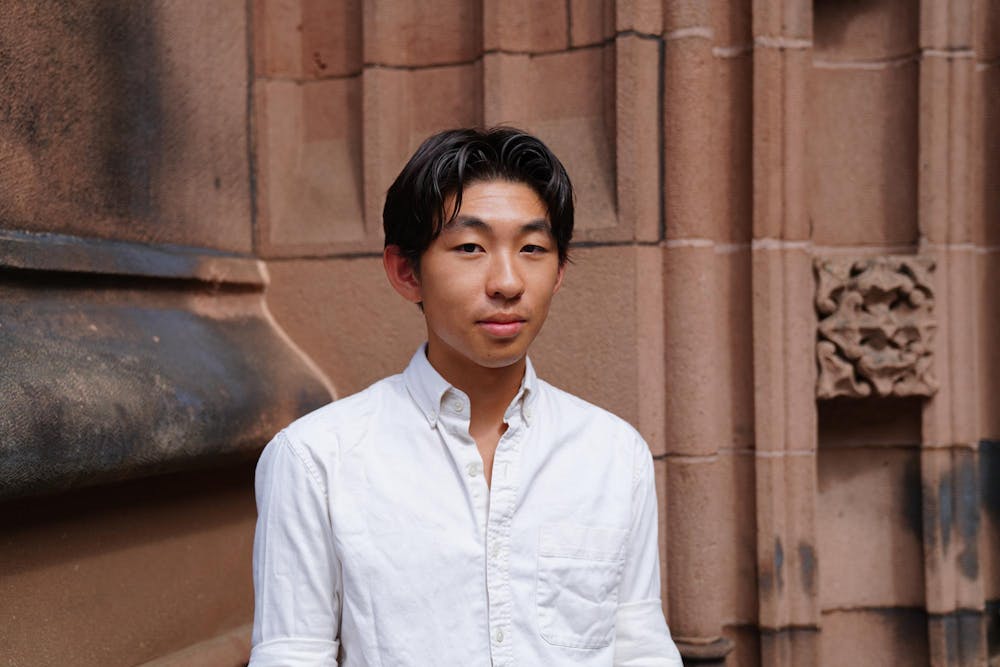 A man standing in front of a building wearing a white button up shirt.
