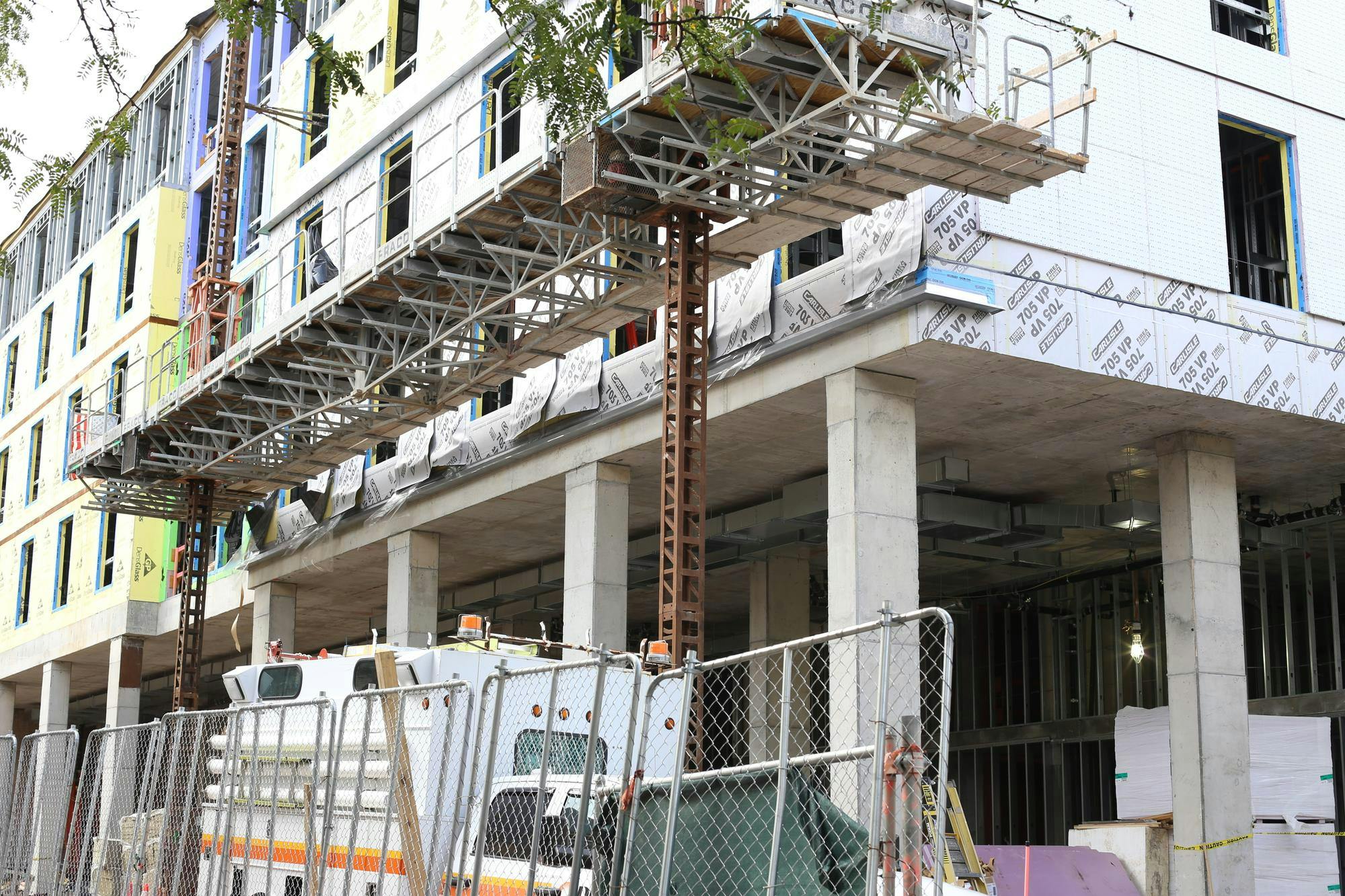 The Graduate Hotel in Princeton under construction. A fence surrounds a metal building being constructed. A construction truck sits behind the fence.