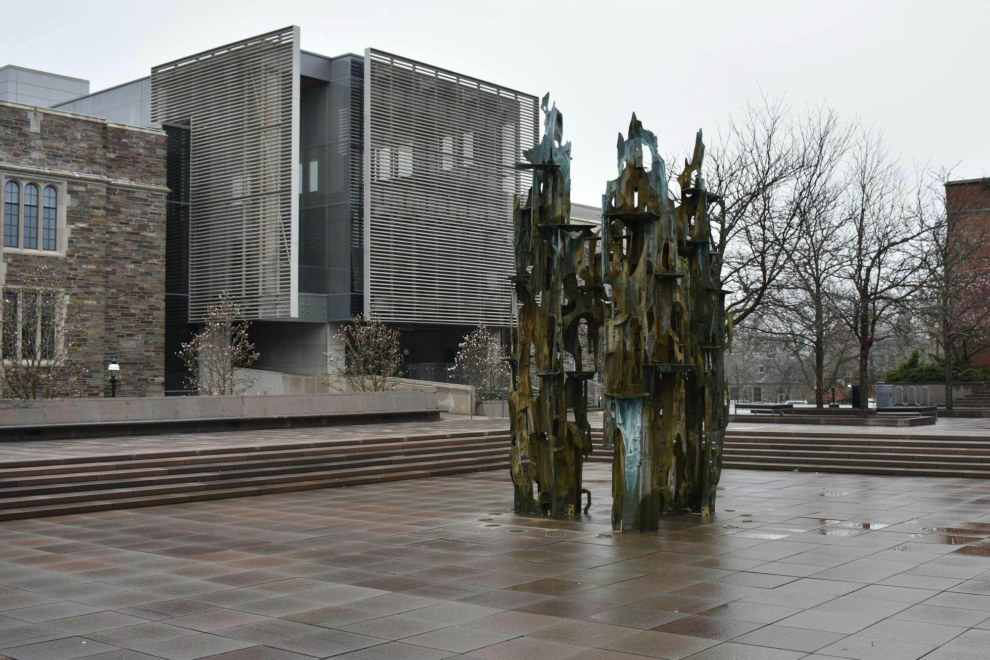 An empty fountain in front of a modern stone building on a rainy day.
