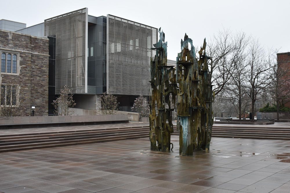 An empty fountain in front of a modern stone building on a rainy day.