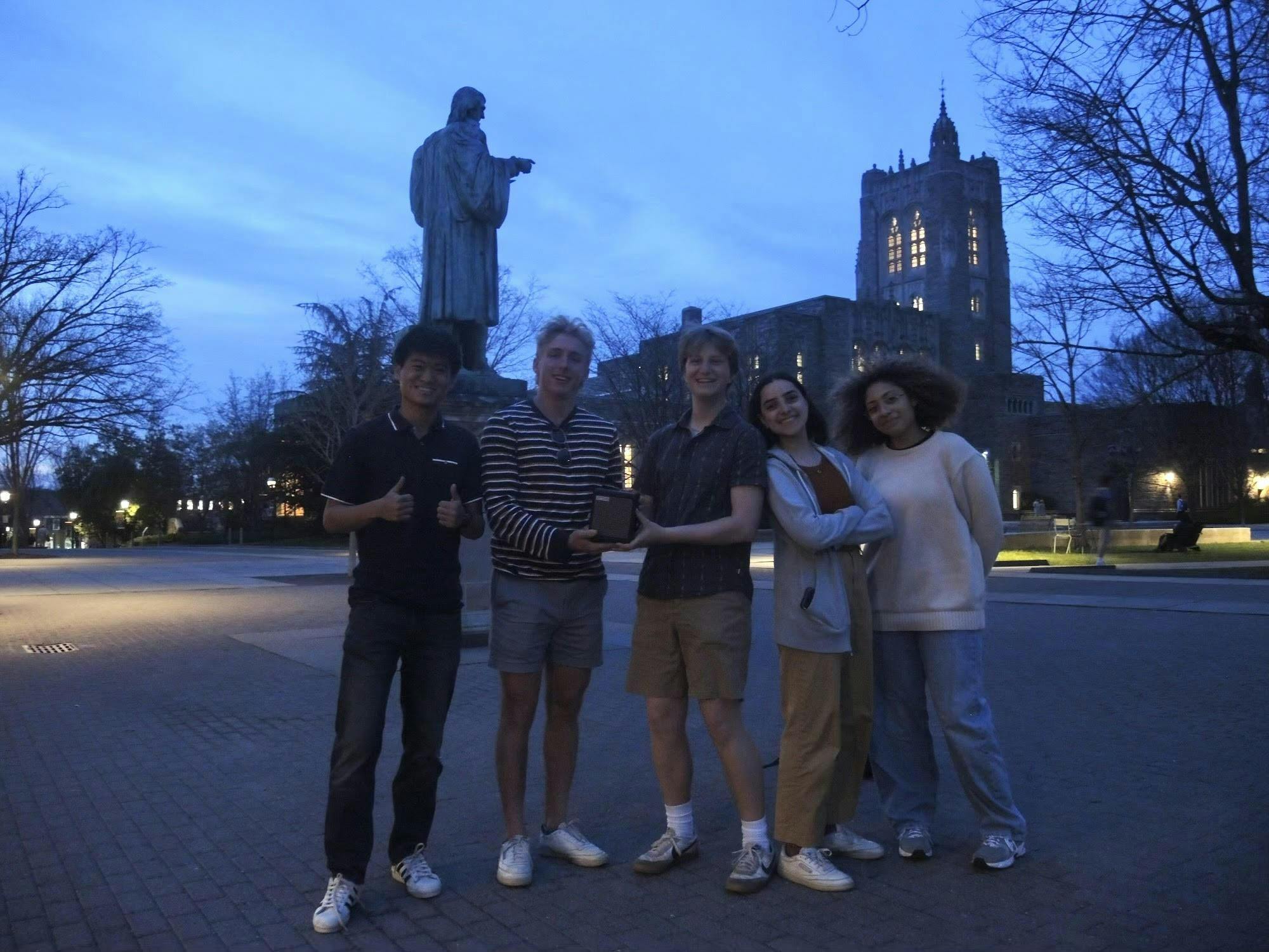 Five students standing in a plaza.