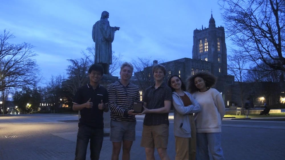 Five students standing in a plaza.