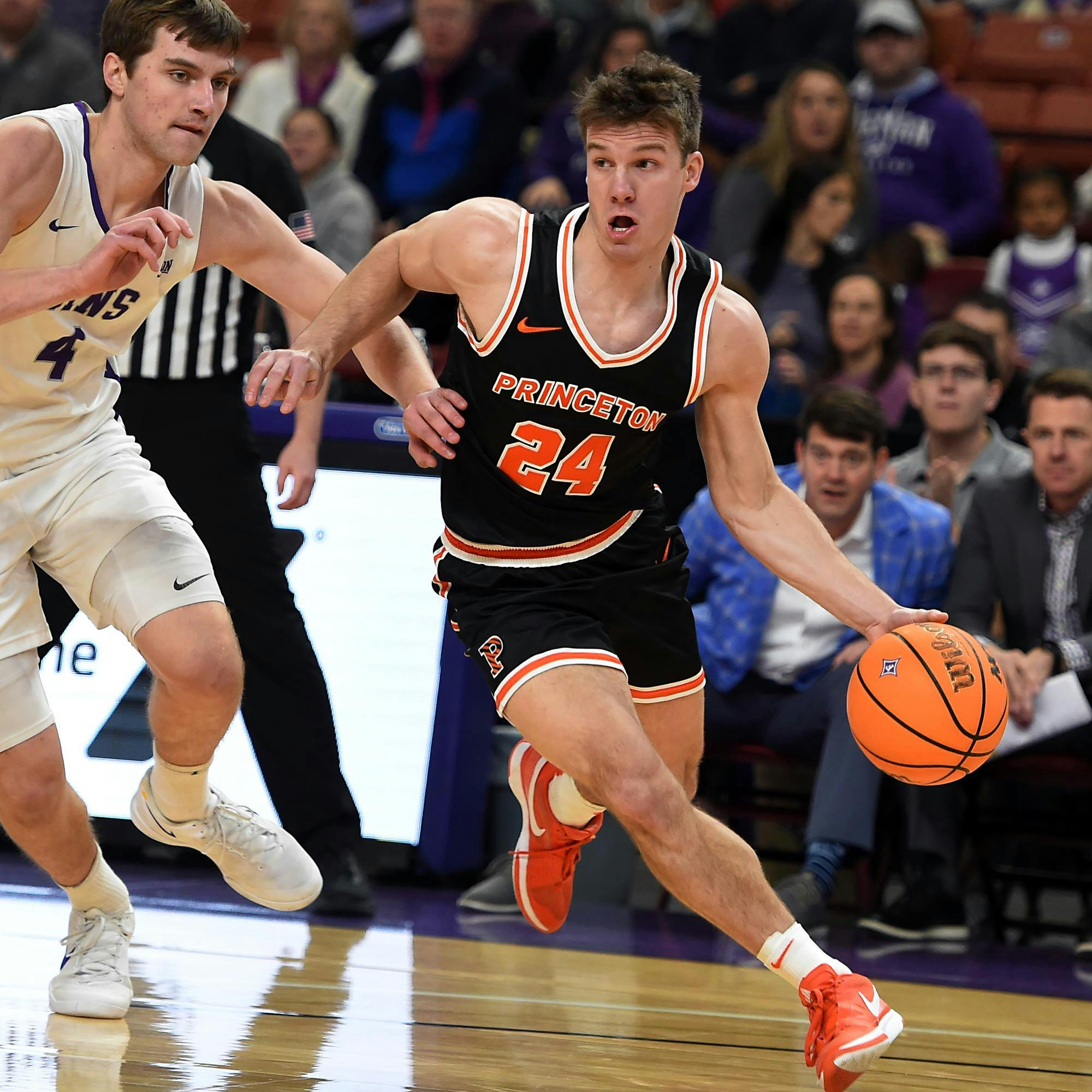 Man runs down a court dribbling a basketball.