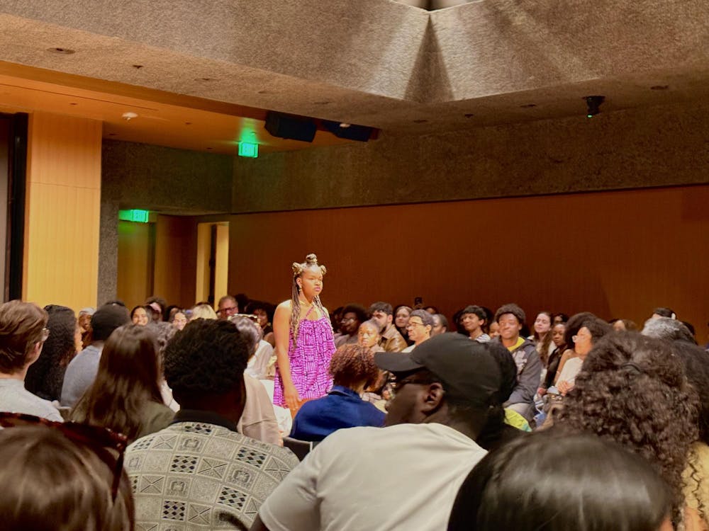 Model on the runway dressed in a pink dress among a crowd of Sankofa attendees. 