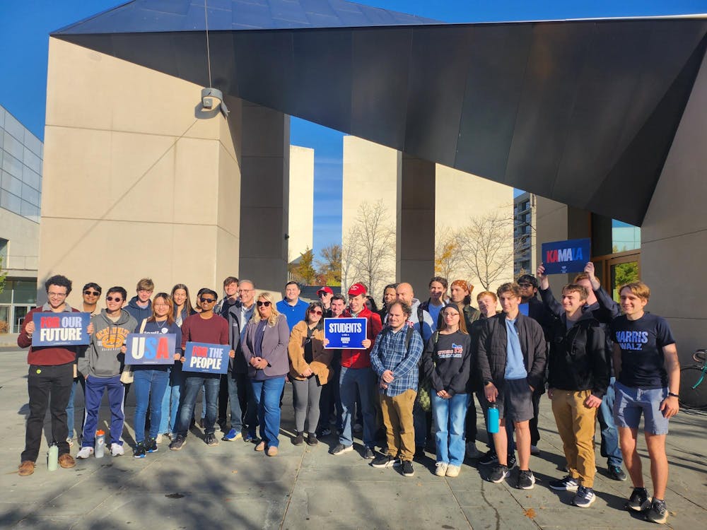 A group of about 30 people standing outside with signs in support of the Harris campaign.