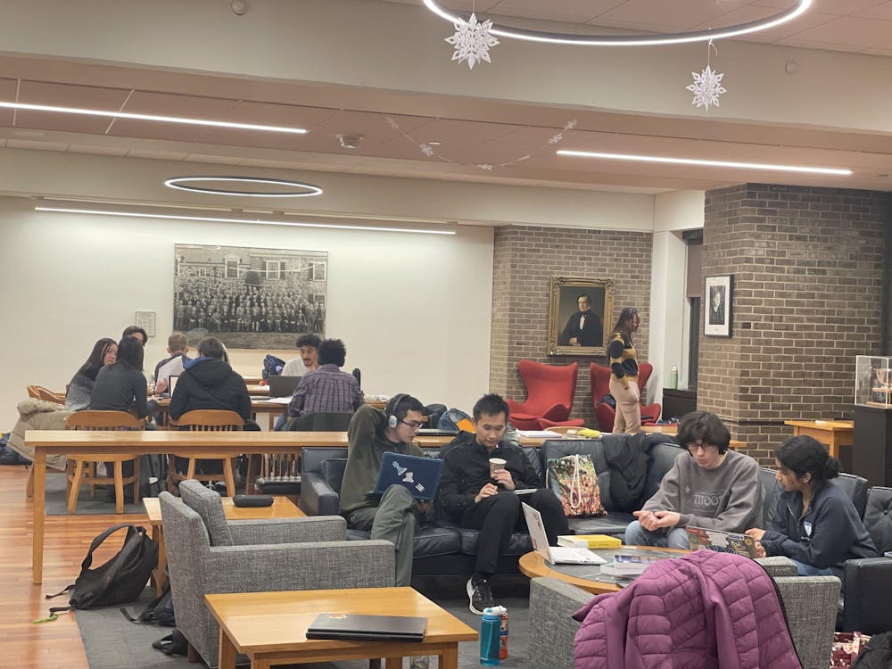 A brightly lit common room with groups of students gathered in it