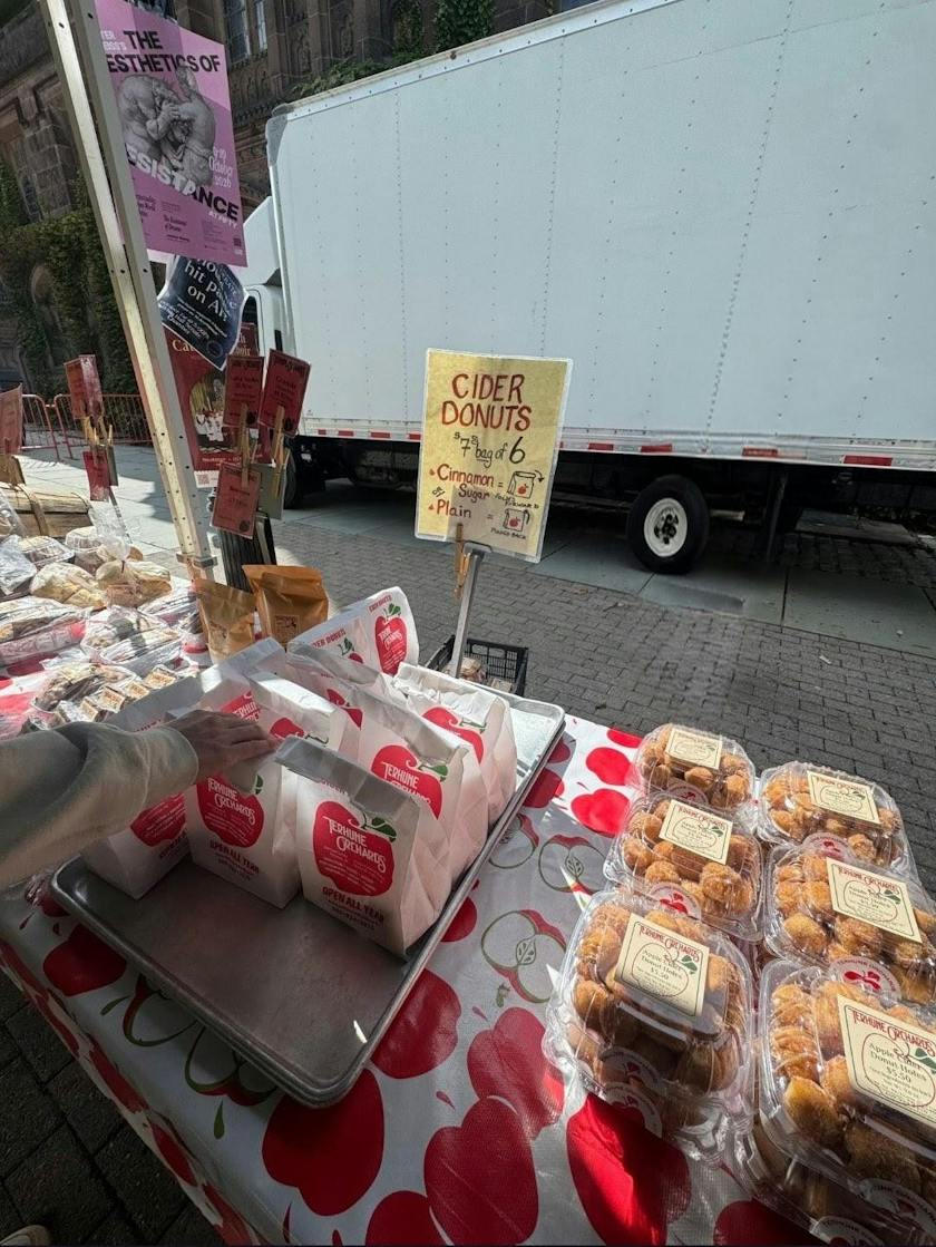 Bags of donuts with an apple logo and plastic containers of pastries are being sold at a stall.