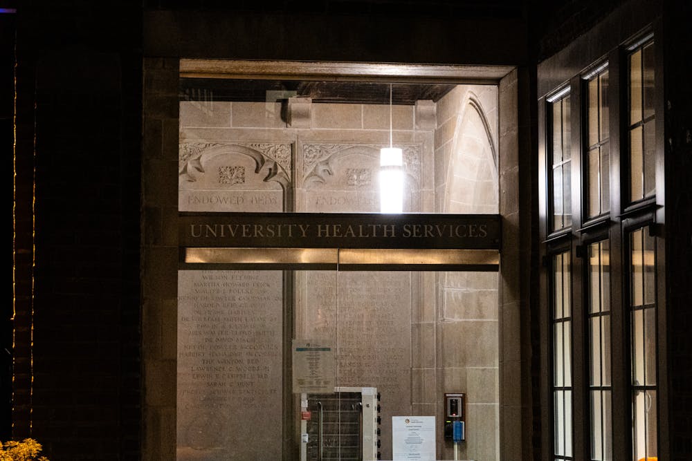 Nighttime view of a glass door with the words “University Health Services”