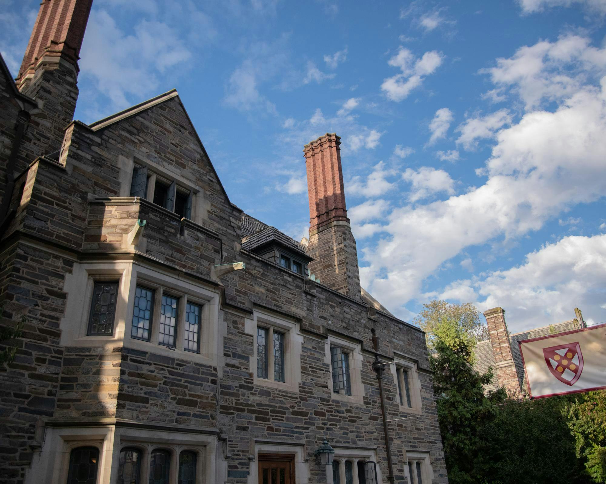 Grey stone building with a triangular silhouette next to a sign with the seal of Mathey college.