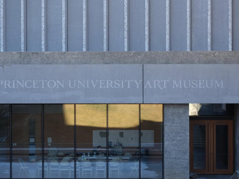 The front of a grey building with the building name "Princeton University Art Museum" plastered above floor-to-ceiling windows and the entryway