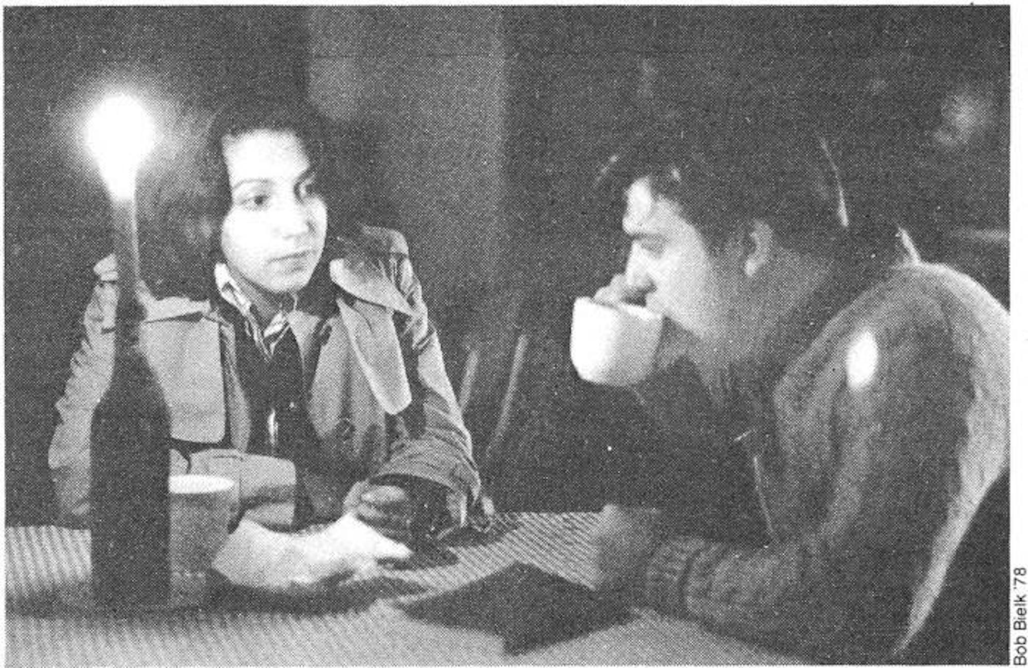 Black and white photo of two students seated sipping coffee in Murray-Dodge café.
