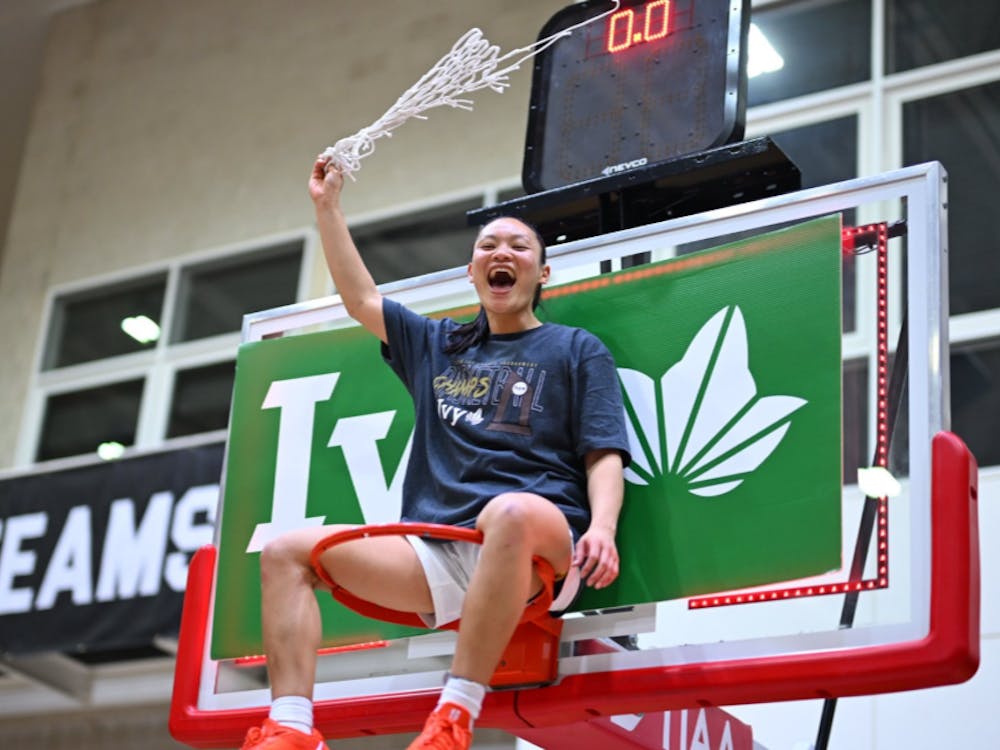 Ashley Chea sitting on a basketball rim.