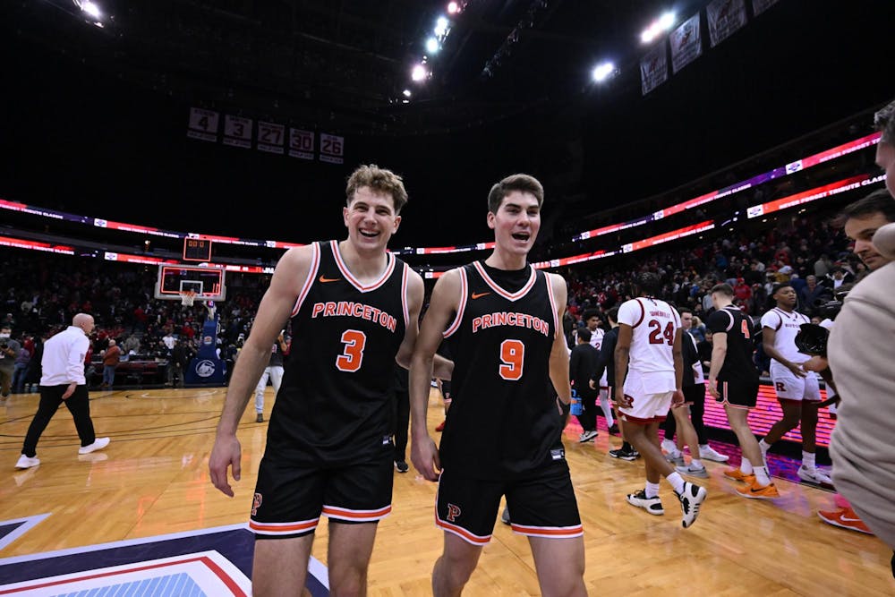 Two men wearing black jerseys smiling on a basketball court after winning a game 