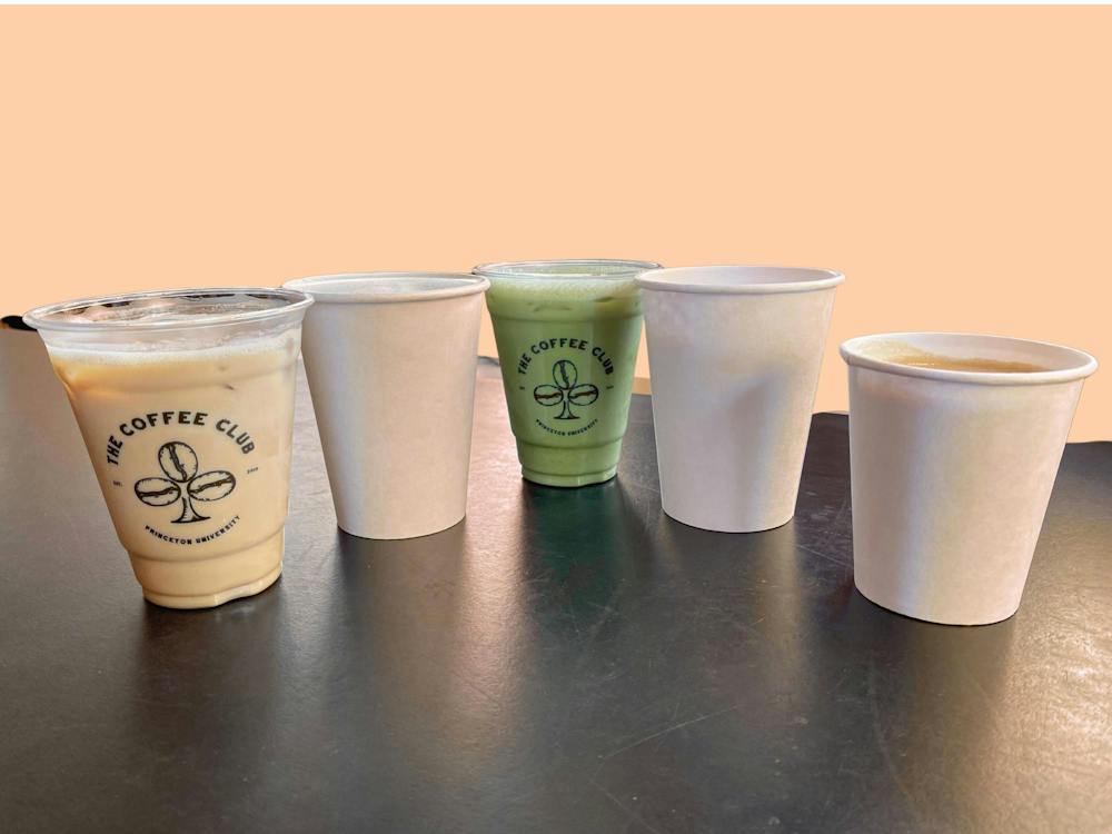 Five drinks sit on a table against a light orange background. 