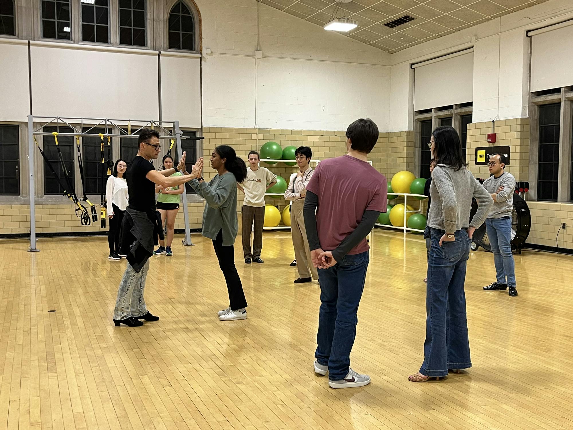 People practicing on a dance floor in a gym.