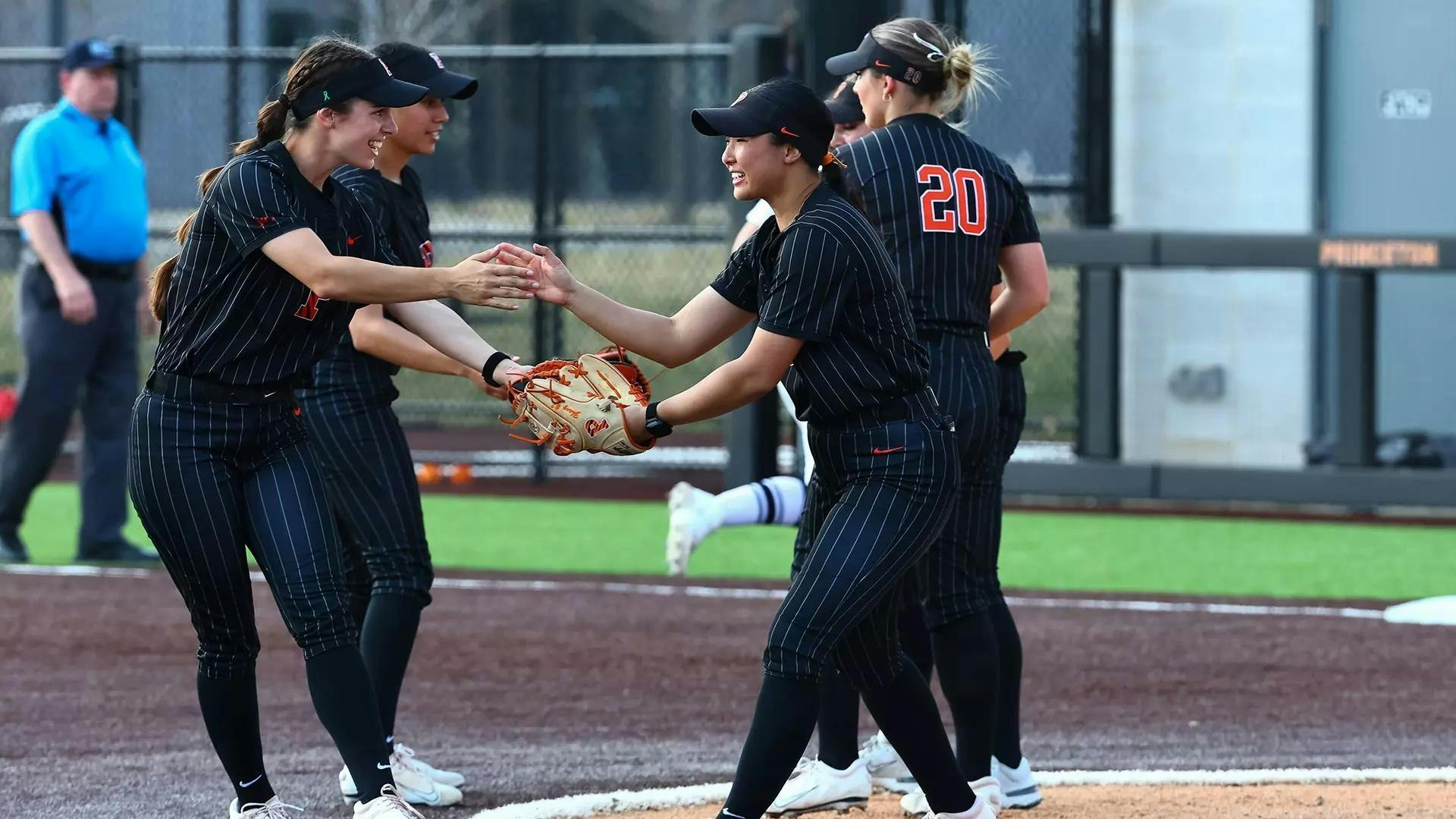 Softball players celebrating on field in uniform.