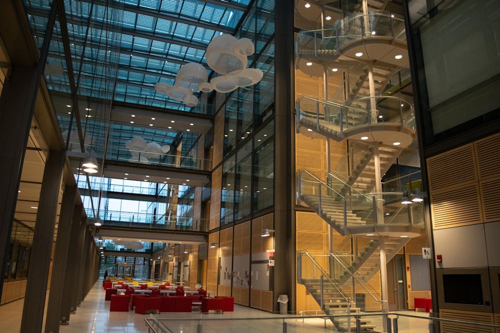 The interior of glass building with floating cloud-like lights and stairs to the right.