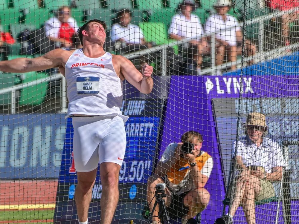 Man in white track uniform throw a discus in the discus throw event.