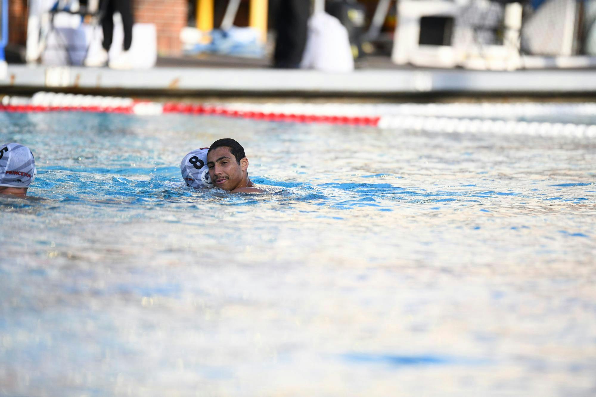 Two men in the water hug each other at the end of a water polo game. 
