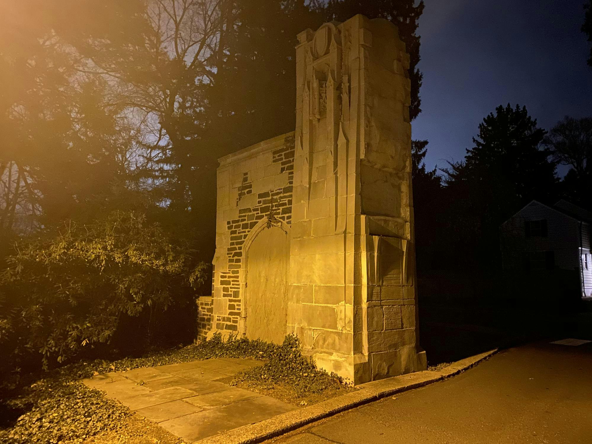 A tall stone column with trees around it late at night.