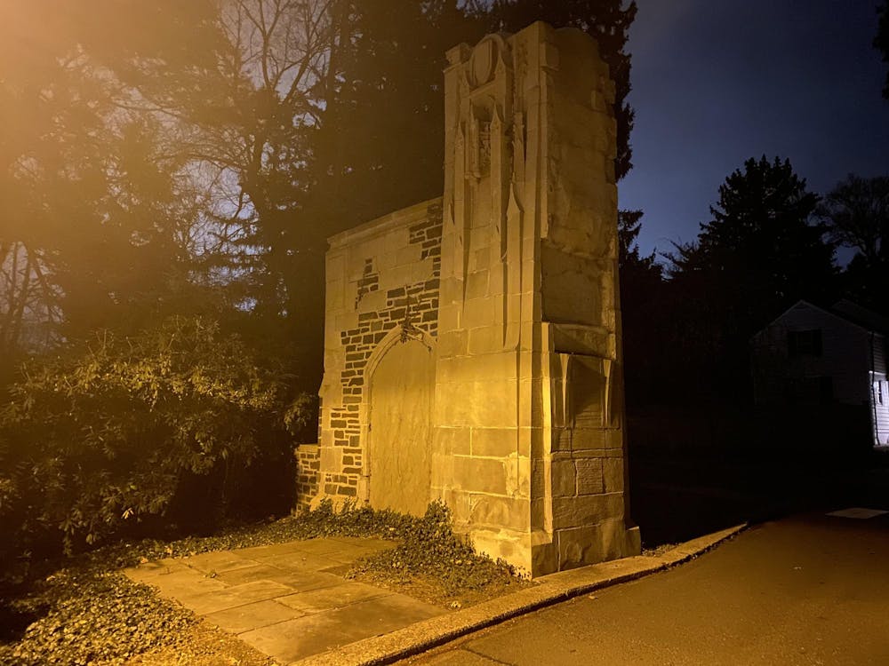 A tall stone column with trees around it late at night.