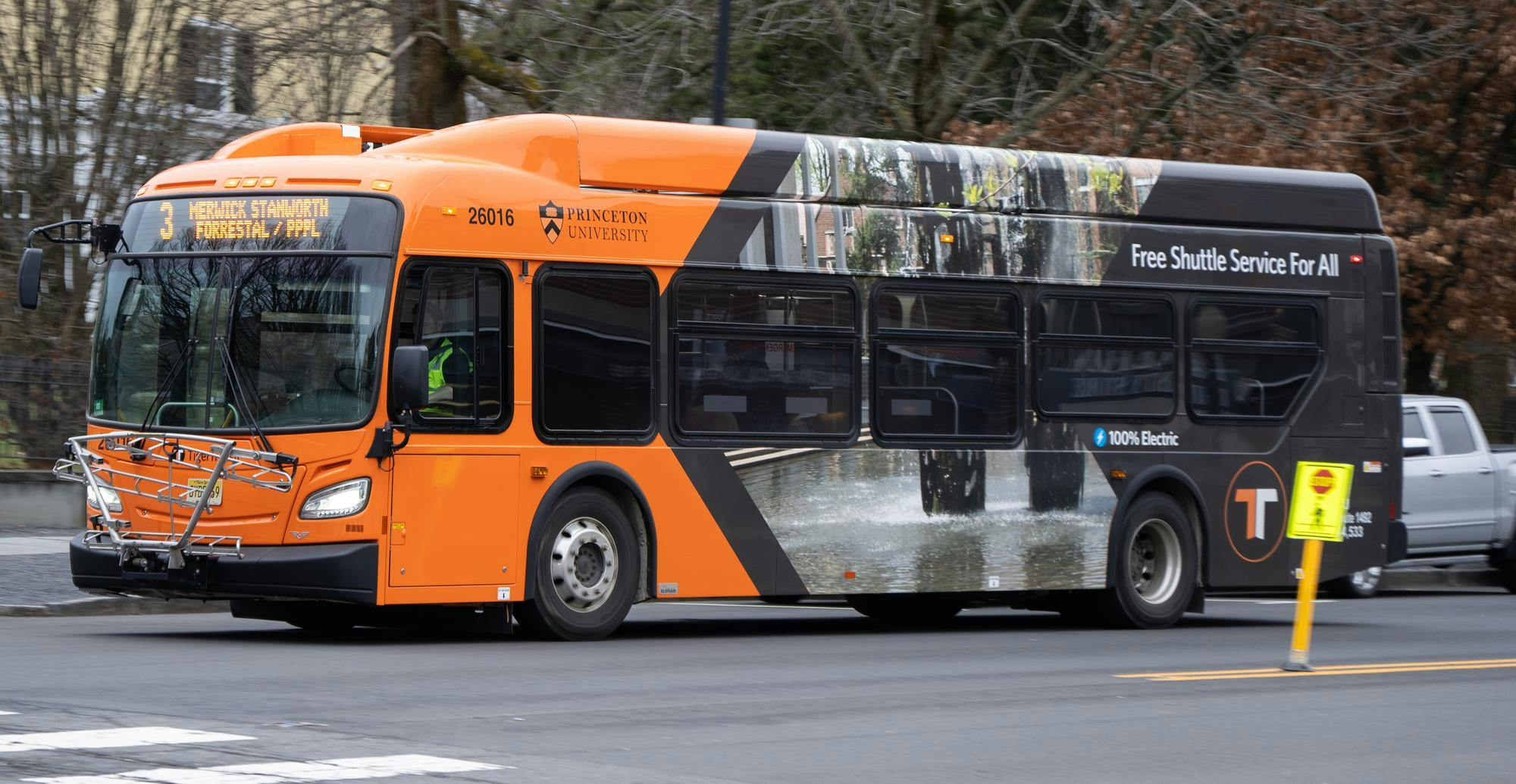 Large orange and black bus on the other side of yellow double line on road.