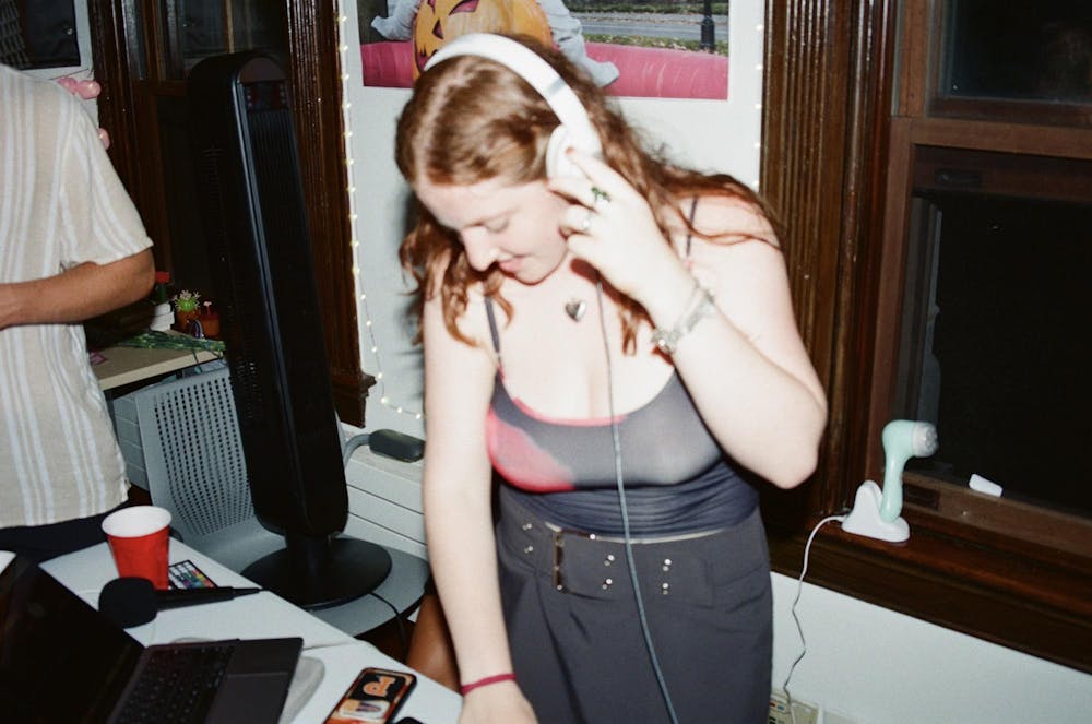 Girl with headphones plays music for others in a college dorm. 