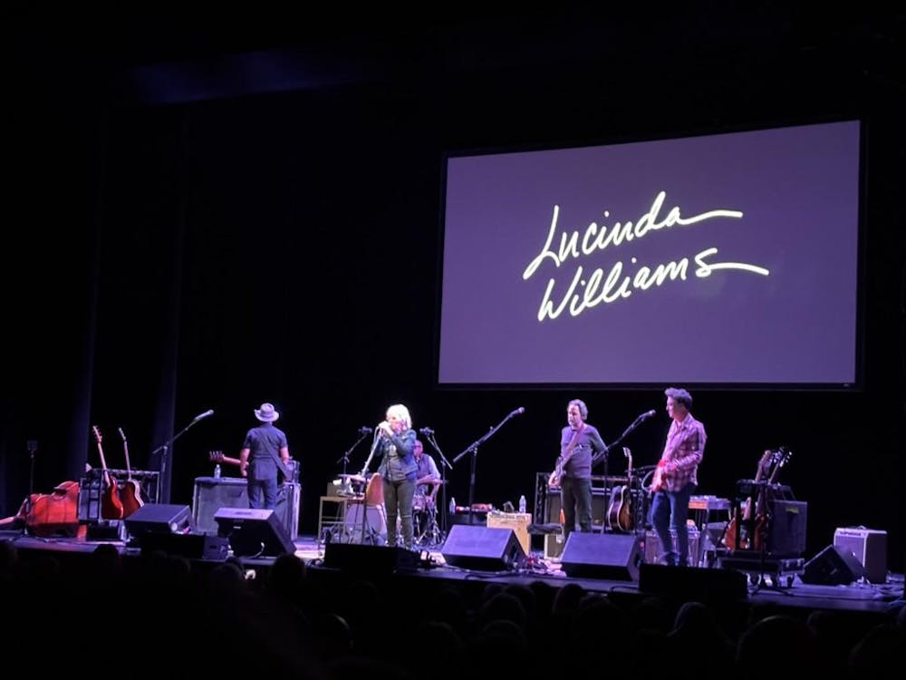  A singer-songwriter stands center-stage with music equipment and speakers all around her.