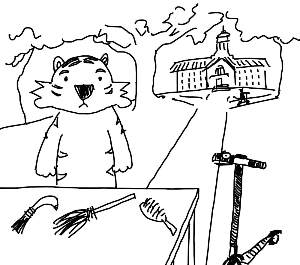 A tiger stands behind a table displaying three different handmade tools: a curved knife, a broom, and a hairbrush. Nassau Hall is in the background. The tiger stands silently, looking ahead. There is no text or dialogue.  