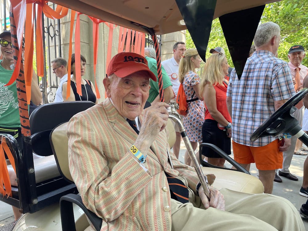 An elderly man sitting on a golf cart in a beige suit.