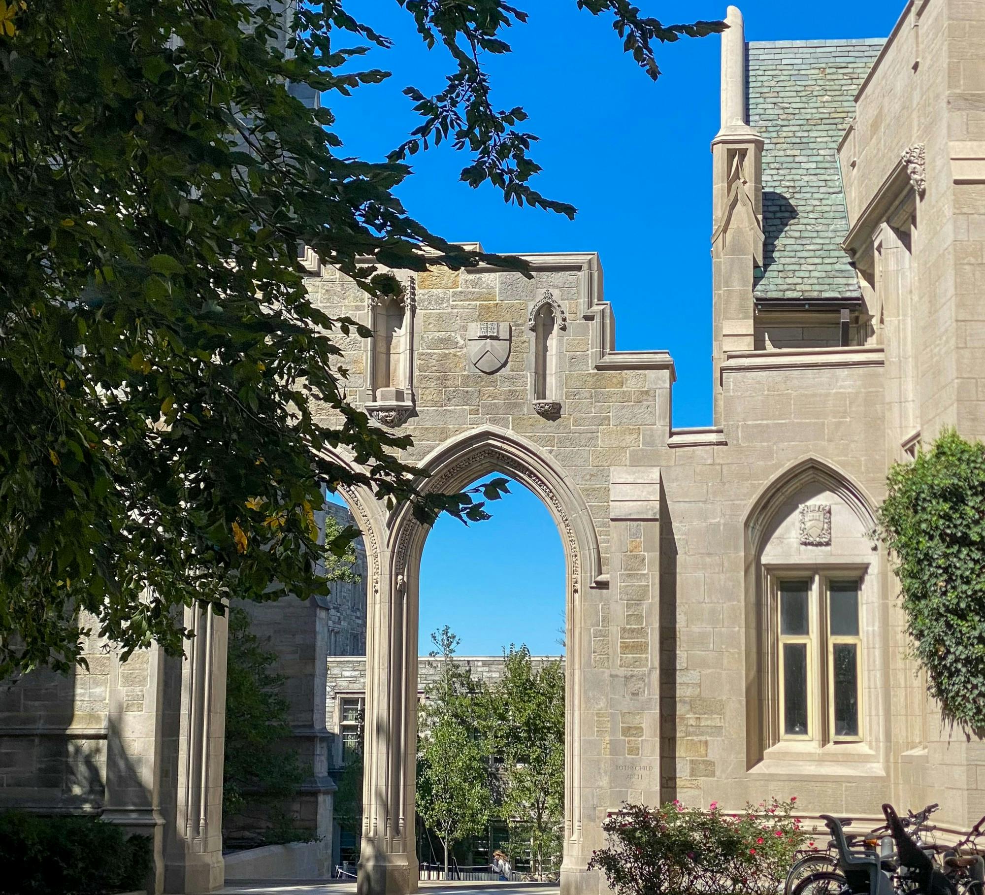 A photo of the arch between Dickinson Hall and the University Chapel: a high stone double gothic arch with a blue sky behind.