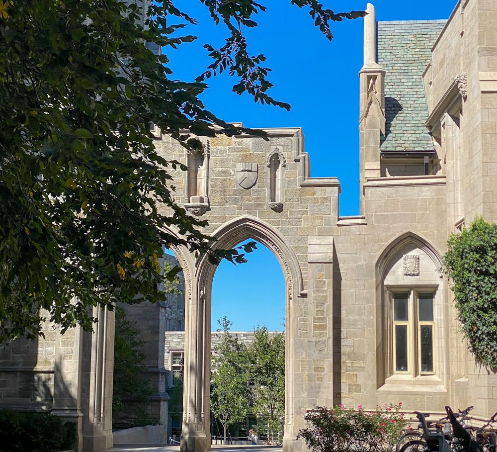 A photo of the arch between Dickinson Hall and the University Chapel: a high stone double gothic arch with a blue sky behind.