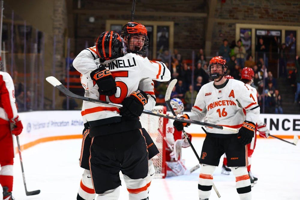 Two players in white uniforms hugging each other and celebrating with another player skating towards them.