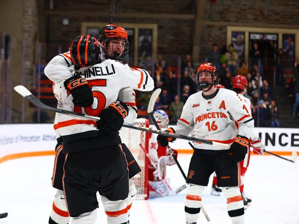 Two players in white uniforms hugging each other and celebrating with another player skating towards them.