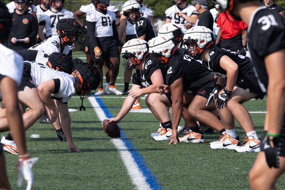 Two sides of football players line up against each other on a field, prepared to snap the ball.